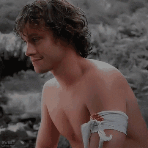 a shirtless man with a bandage on his arm is smiling and looking away from the camera
