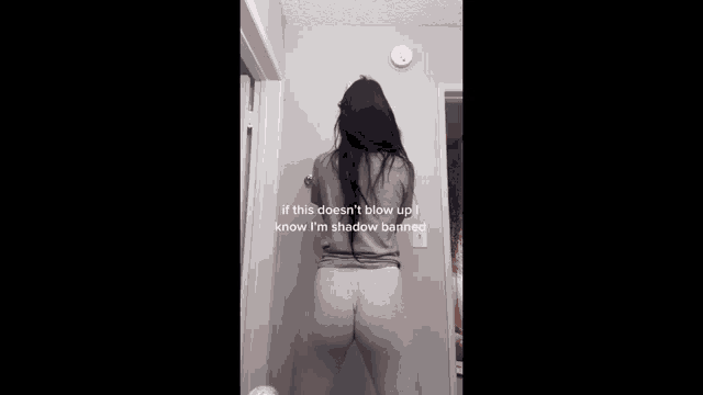 a woman is standing in front of a door in a room and making a funny face .
