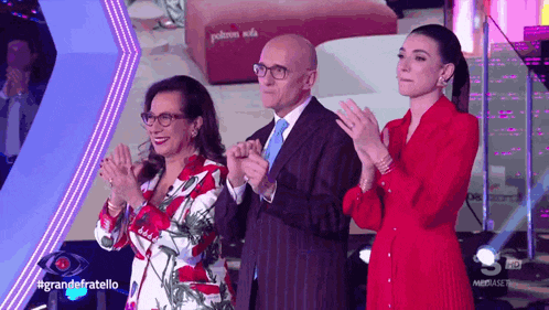 a group of people applauding in front of a sign that says grande fratello