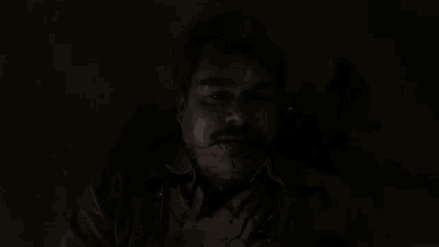 a man with blood coming out of his mouth is laying on the floor in the dark .