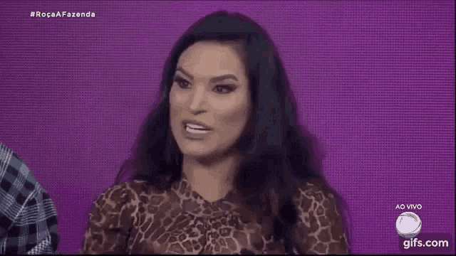 a woman in a leopard print top is making a funny face while covering her mouth with her hands .