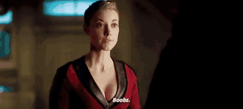 a woman in a red top is talking to a man in a dark room and says boobs .