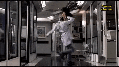 a man in a lab coat is jumping in a hallway with simone saltarelli written on the bottom right