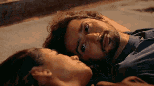 a man and a woman laying on a bed with their eyes closed