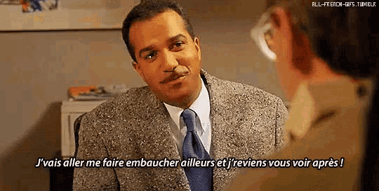 a man in a suit and tie is talking to another man in an office .