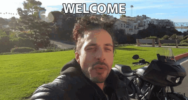 a man blowing a kiss next to a motorcycle with the words welcome above him