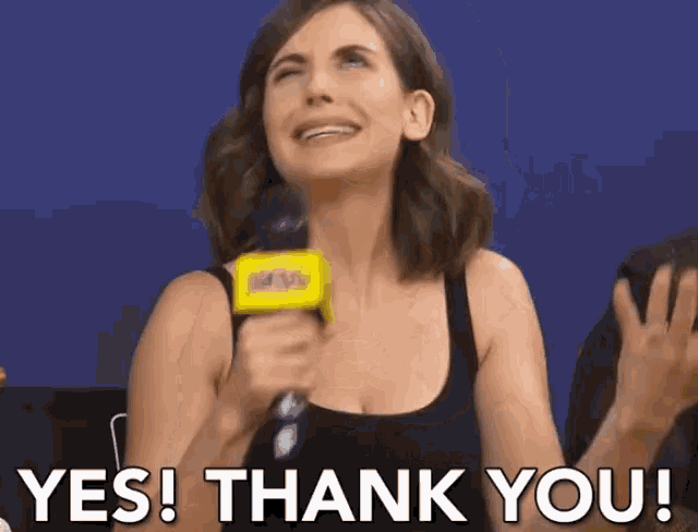 a woman is holding a microphone and saying yes thank you .