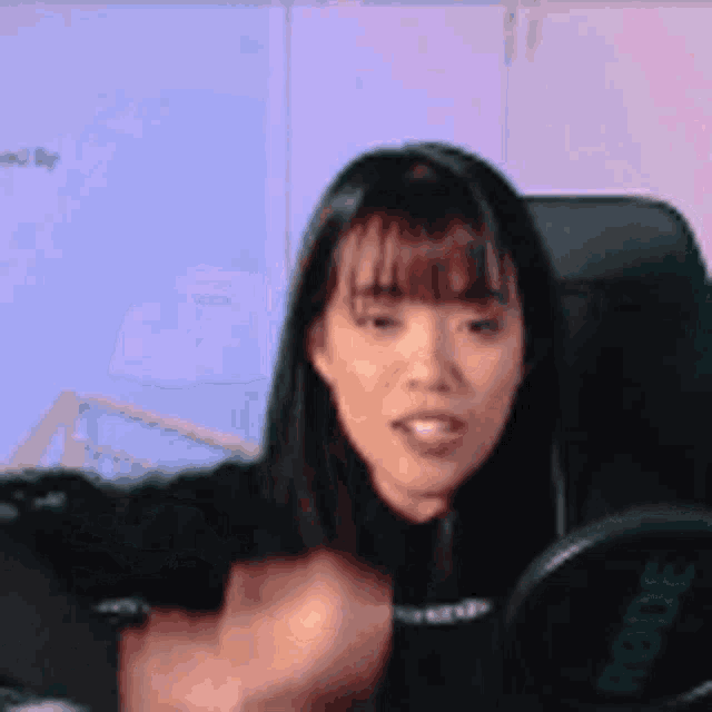 a woman is sitting in front of a rode microphone and making a funny face .