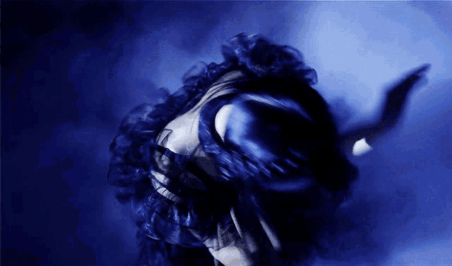 a woman in a blue dress covering her face with her hand