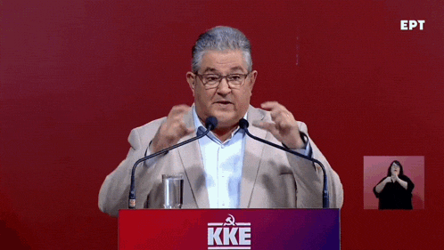 a man stands behind a podium that says kke