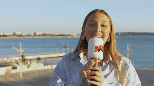 a woman is holding a microphone with the letter r on it and smiling