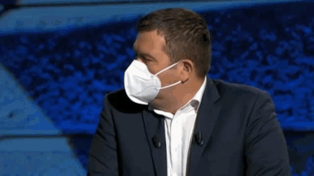 a man in a suit is wearing a mask on his face