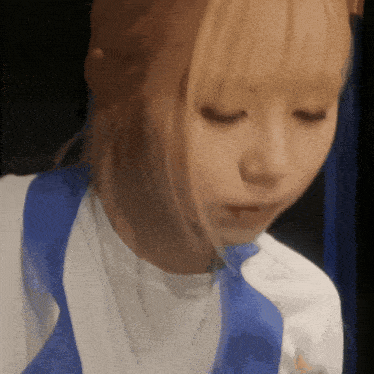 a woman wearing a white shirt and a blue vest looks down