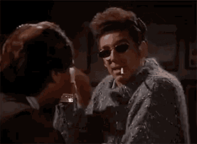 a man is smoking a cigarette in a bar while talking to another man .