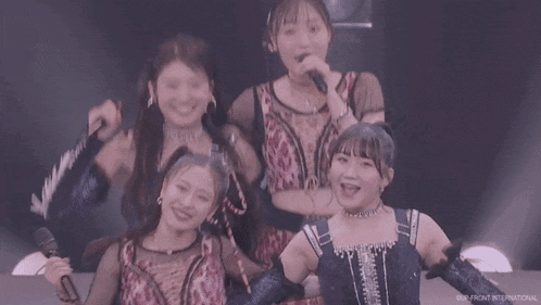 a group of young women are singing into microphones while standing next to each other .