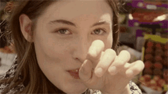 a close up of a woman 's face with her fingers in her mouth