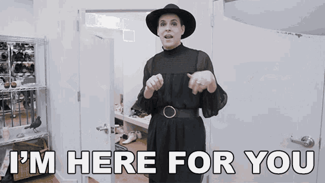a woman in a black dress and hat says " i 'm here for you " in front of a door