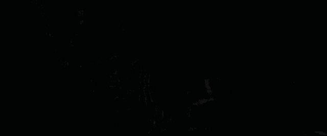 a cat in a dark room with a thumbs up