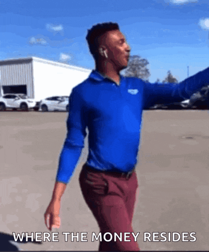 a man in a blue shirt and red pants is dancing in a parking lot with the words where the money resides above him