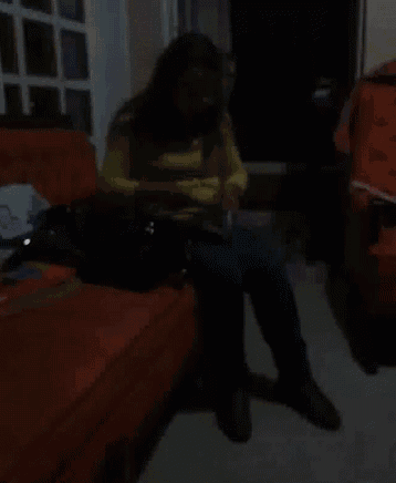 a woman in a yellow shirt is sitting on an orange couch
