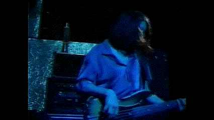 a woman in a blue shirt is sitting in a dark room