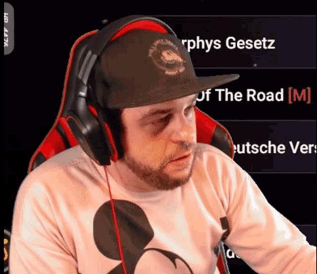 a man wearing headphones and a mickey mouse shirt looks at the camera