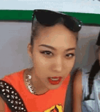 a woman wearing sunglasses and a necklace is making a funny face .