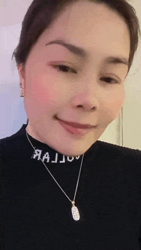 a woman wearing a black turtleneck and a necklace with the word majju on it