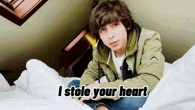 a young boy is sitting on a bed with the words i stole your heart
