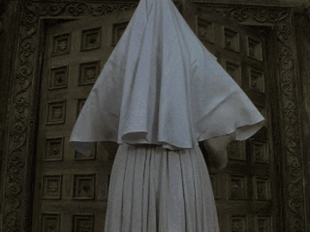 a woman in a white robe stands in front of a door