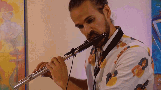 a man is playing a flute in front of a colorful painting