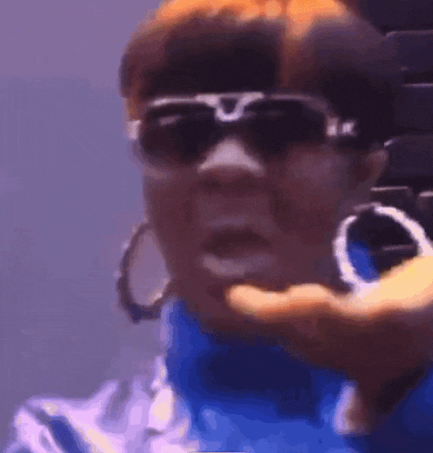 a woman wearing sunglasses and hoop earrings is making a funny face .