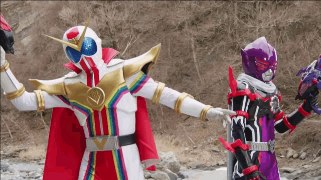 two superheros are standing next to each other in a field holding their arms up .