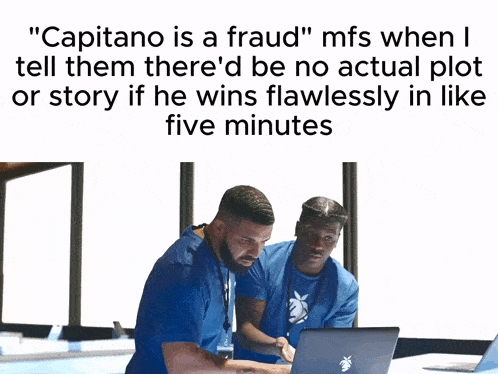 a man in a blue shirt sits in front of a laptop