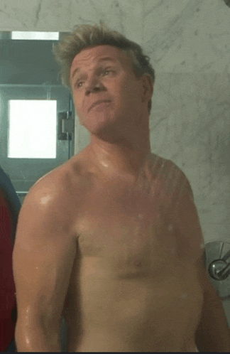 a shirtless man is standing in a shower looking at the camera