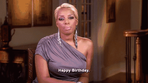 a woman in a gray dress is saying happy birthday .