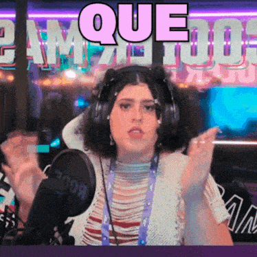 a woman wearing headphones stands in front of a microphone with the word que written in pink