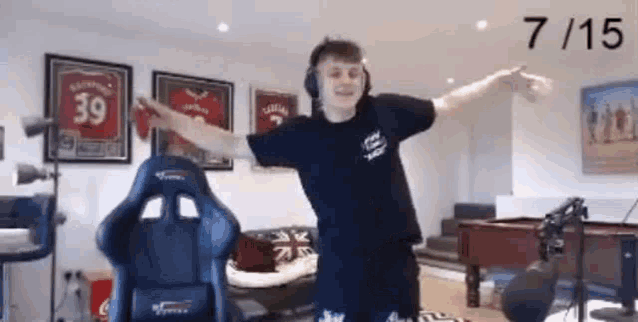 a man is standing in a living room with his arms outstretched and a pool table .