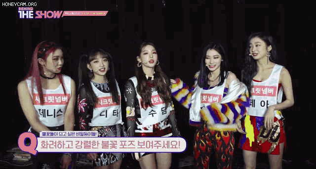 a group of girls standing next to each other with a sign that says behind the show