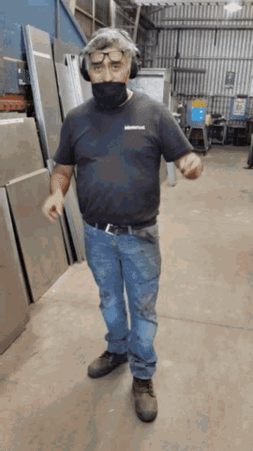 a man wearing a mask and headphones stands in a factory