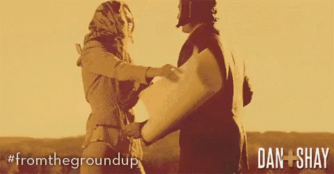 a man is hugging another man in a field with the words from the groundup on the bottom .