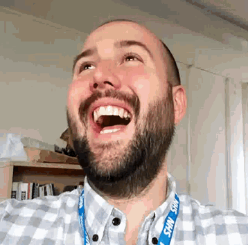a man wearing a lanyard that says nhs is laughing