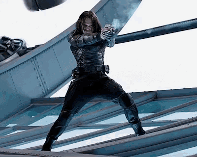a man in a superhero costume is holding a gun while standing on a roof .