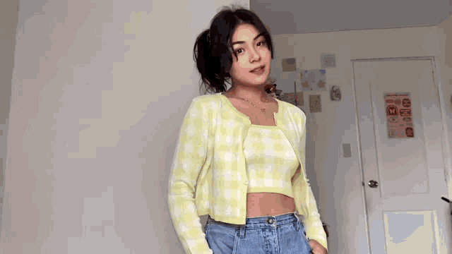 a young woman is wearing a yellow cardigan and a plaid top .