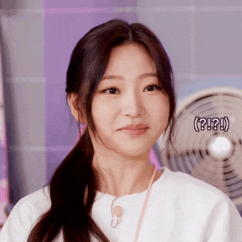 a close up of a woman 's face with a fan in the background and the words ( ? ! ? ) below her