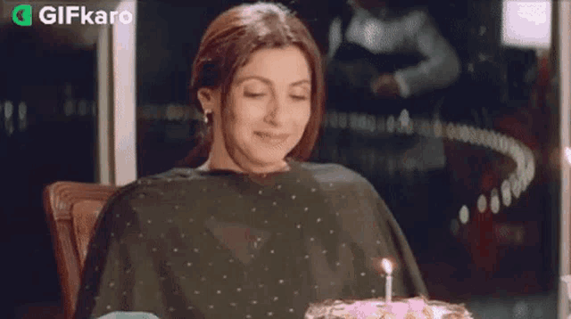 a woman blowing out a candle on a birthday cake .