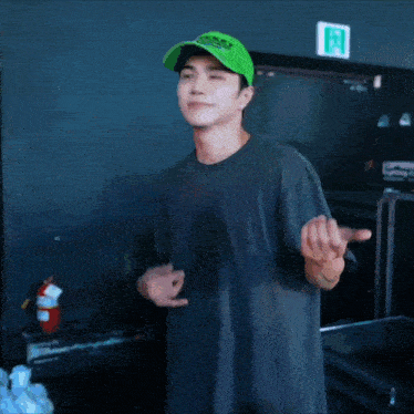 a man wearing a green tekken hat stands in front of a fire extinguisher