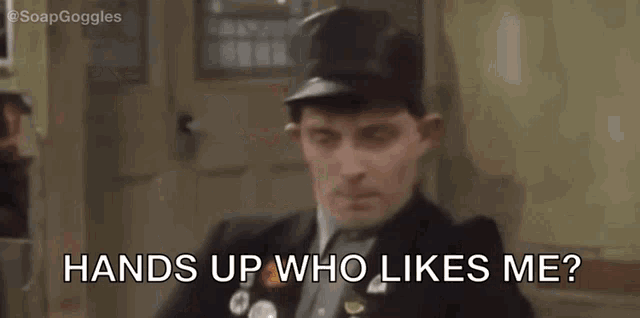 a group of people are sitting at a table and one of them is asking another person , hands up who likes me ?
