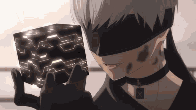 a man wearing a blindfold holds a black cube in his hand