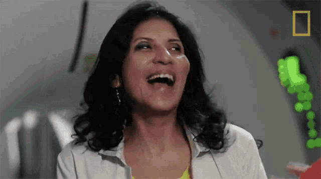 a woman is laughing with a national geographic logo behind her